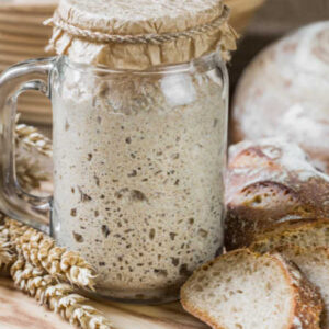 sourdough starter in a jar bubbling to the rim
