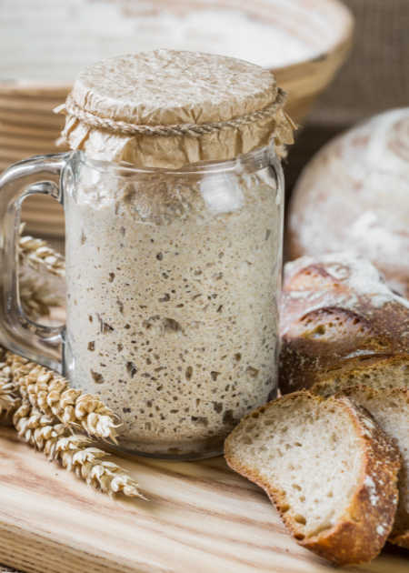sourdough starter in a jar bubbling to the rim